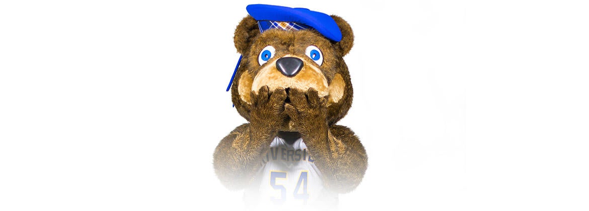 Photo of Scotty the bear with his hands over his mouth.